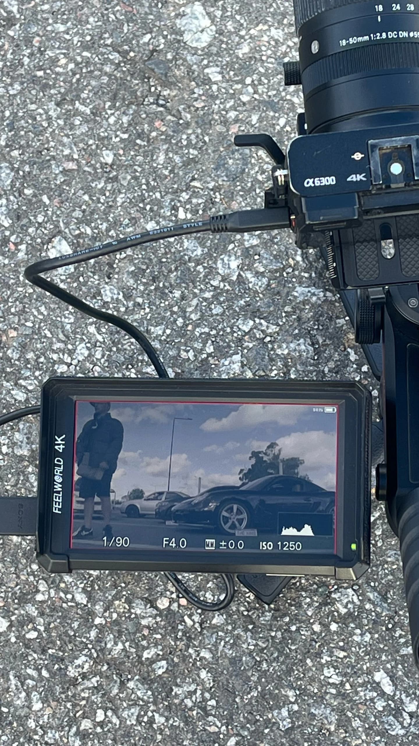 Cámara con monitor externo apoyada en el piso durante una producción de autos