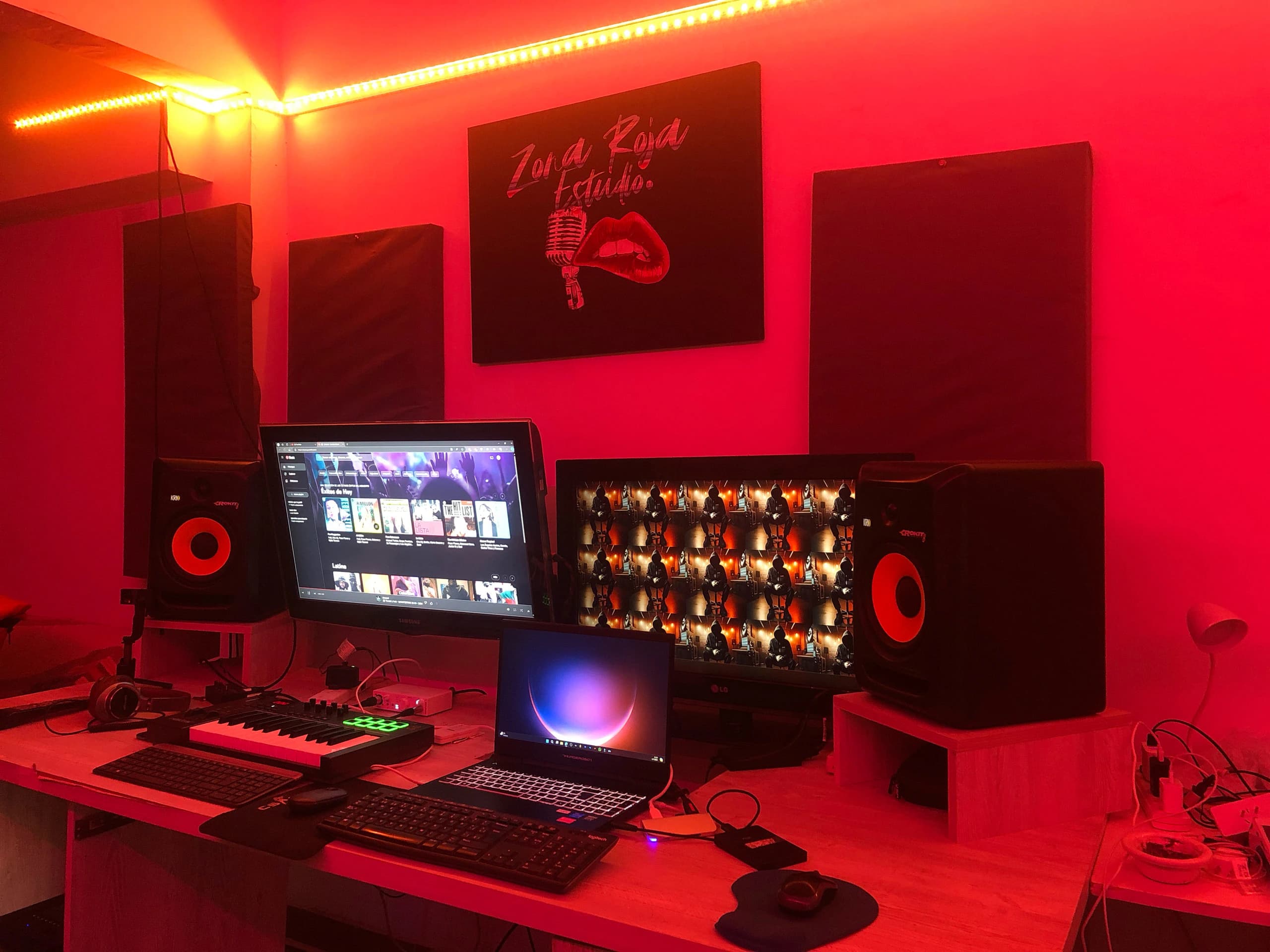 El estudio de Zona Roja iluminado en rojo y naranja, con monitores, monitores de audio y un teclado controlador
